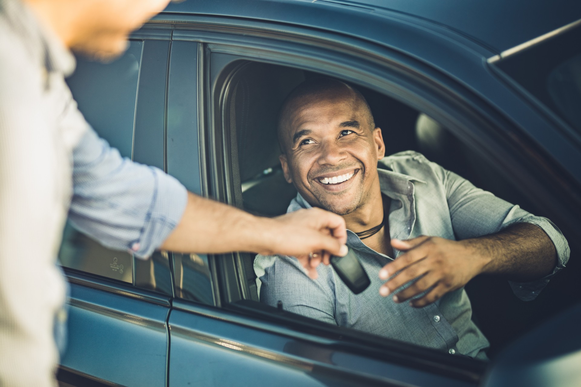 Happy African American businessman taking car keys from a sales person.